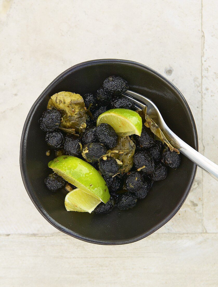 Dried black olives with lime wedges and coriander