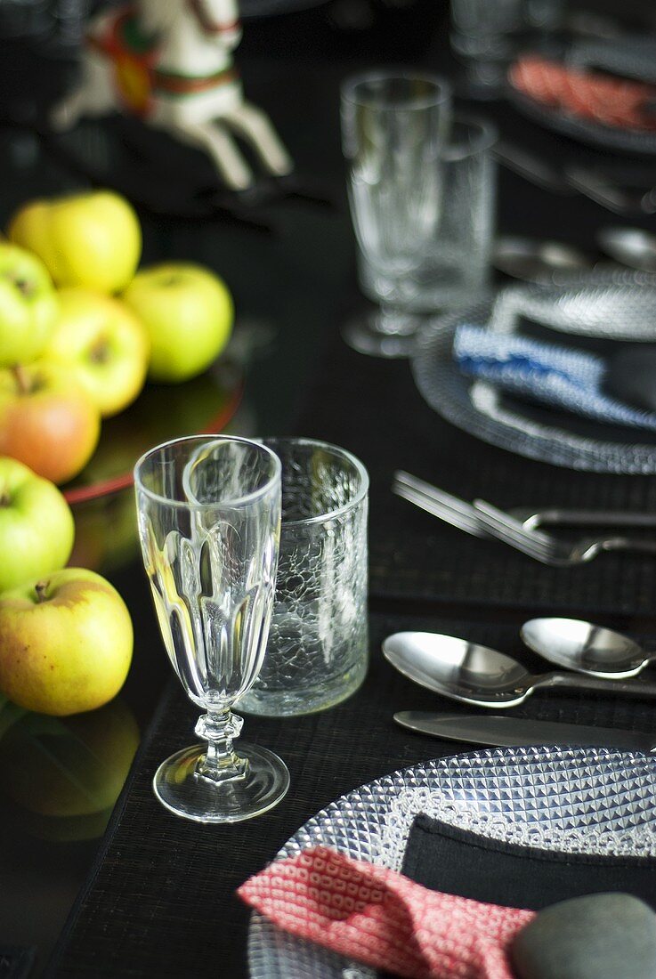 Gedeckter Tisch mit Glastellern und Äpfeln