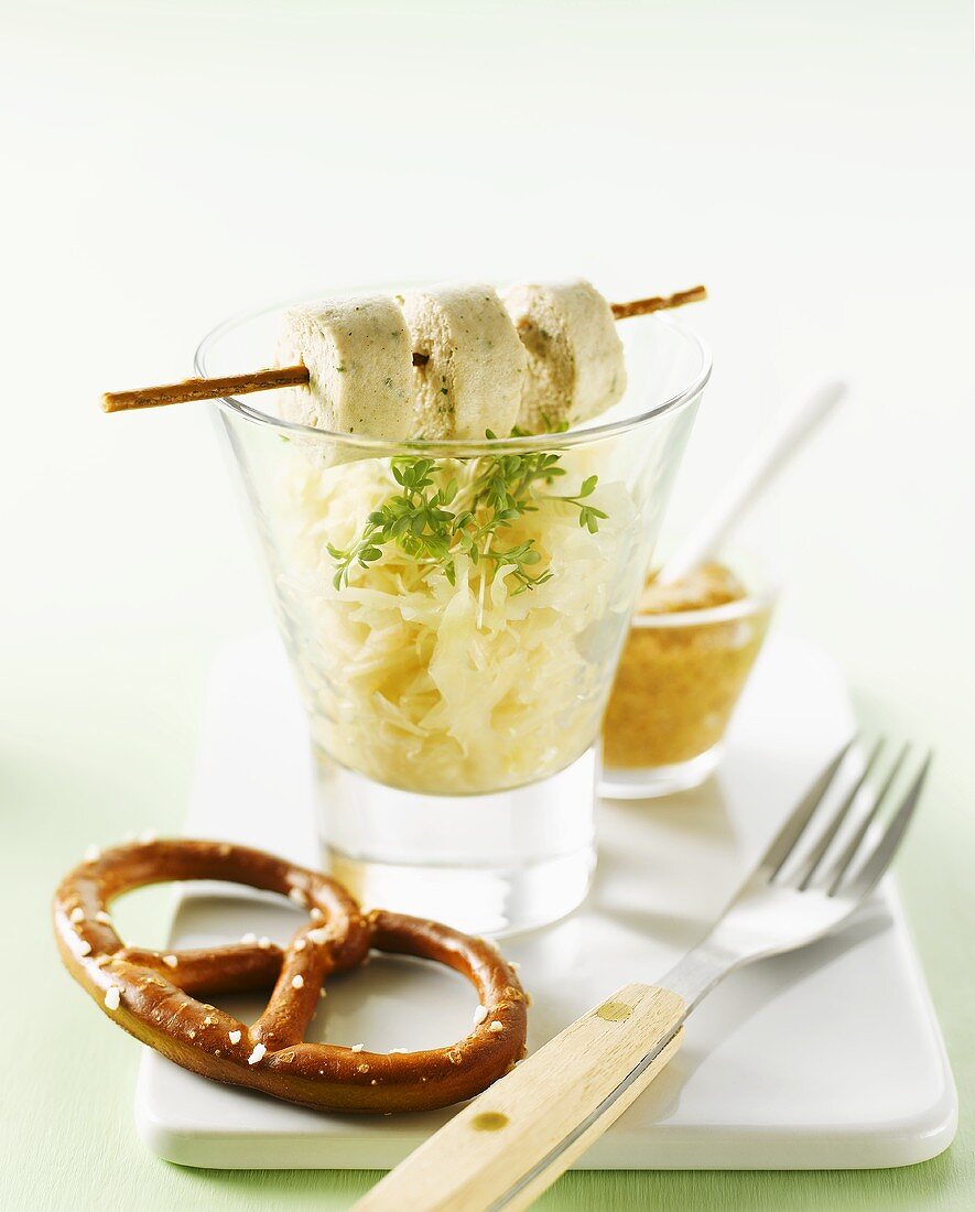 Sauerkraut in glass with slices of white sausage and salted pretzel