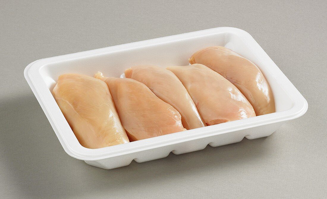 Several chicken breast fillets on plastic tray