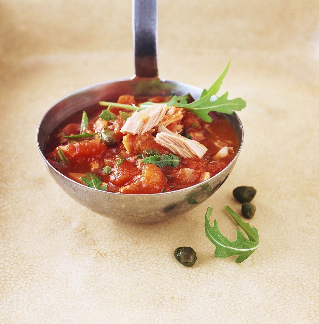 Tomato sauce with tuna, rocket and capers on ladle
