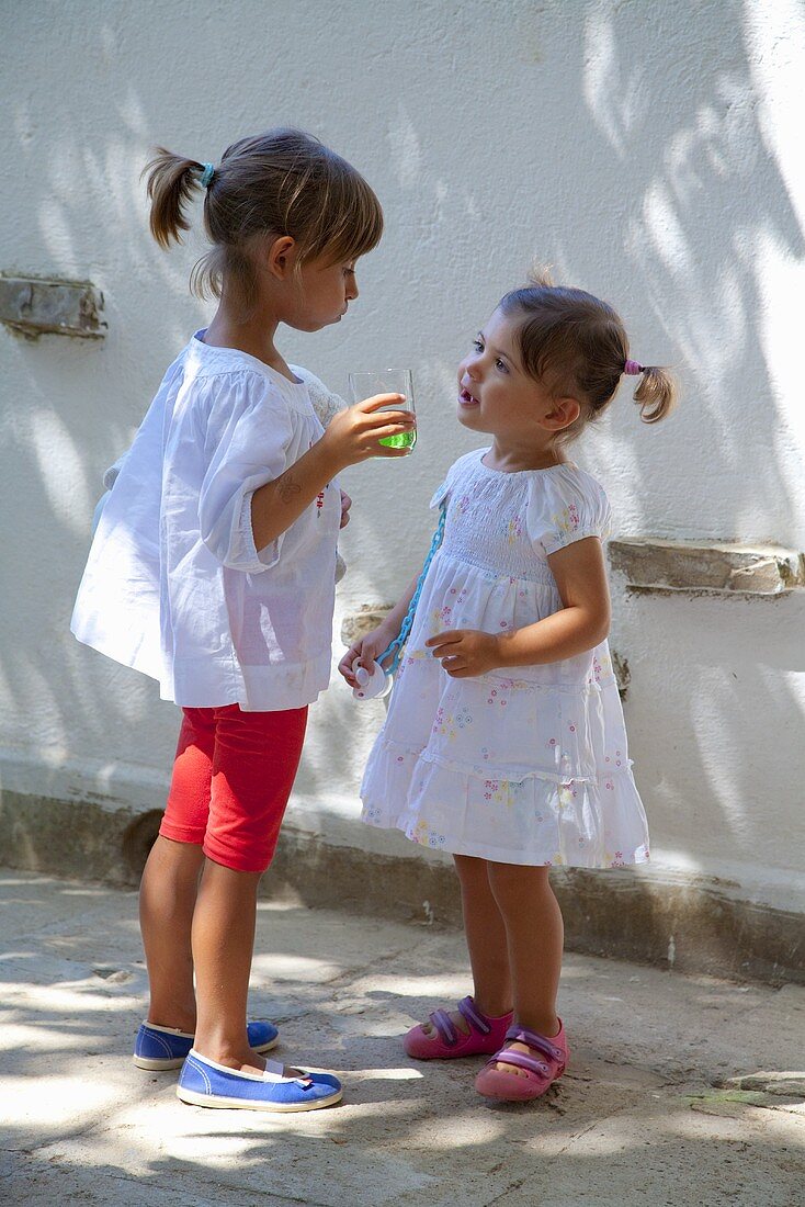 Zwei kleine Mädchen mit Saftglas