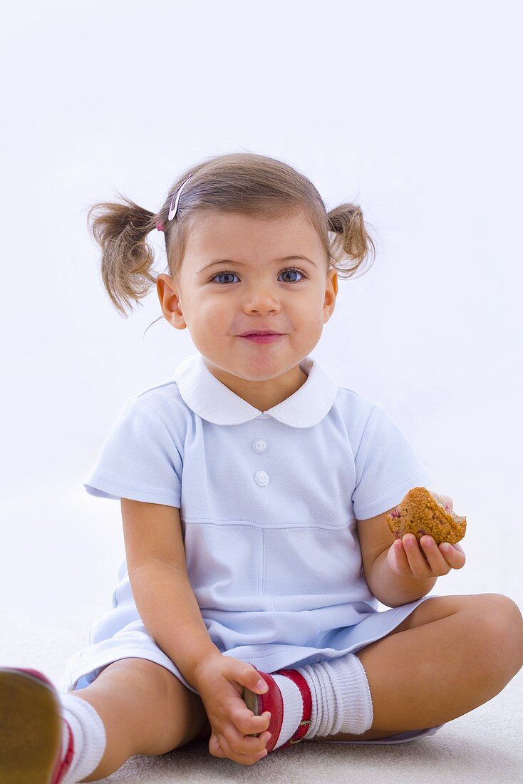 Little girl holding partly eaten muffin