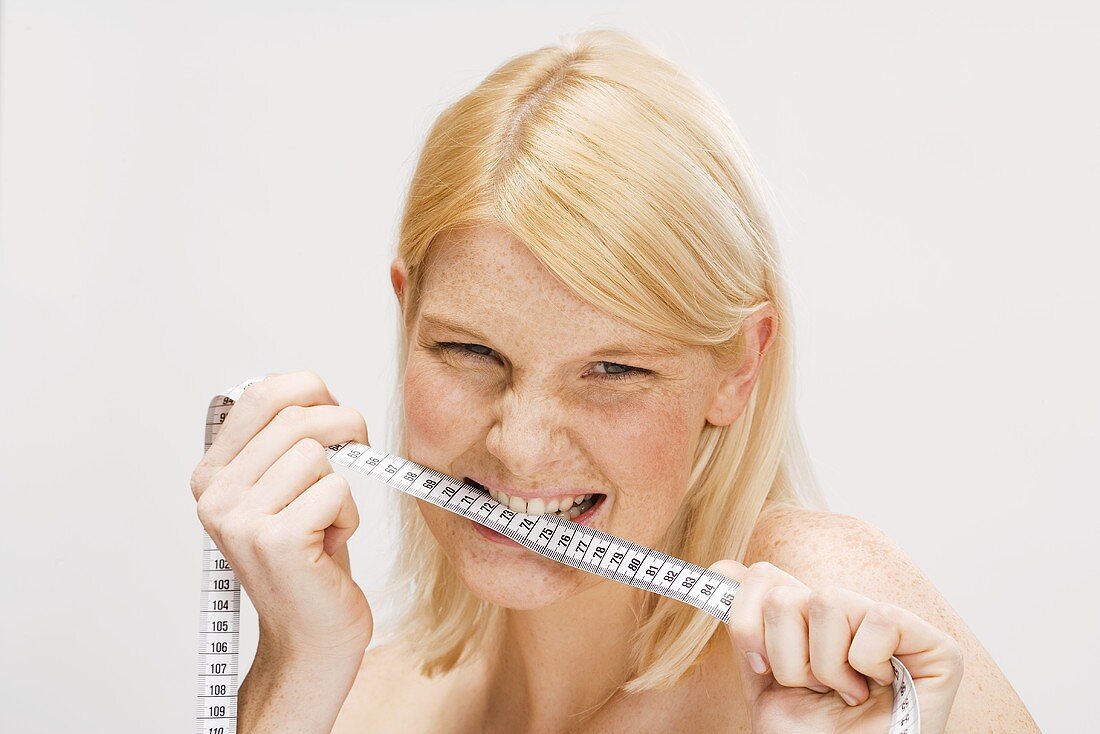 Blond woman biting tape measure