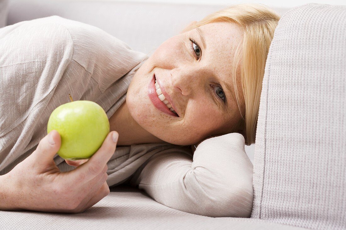 Blonde Frau hält grünen Apfel
