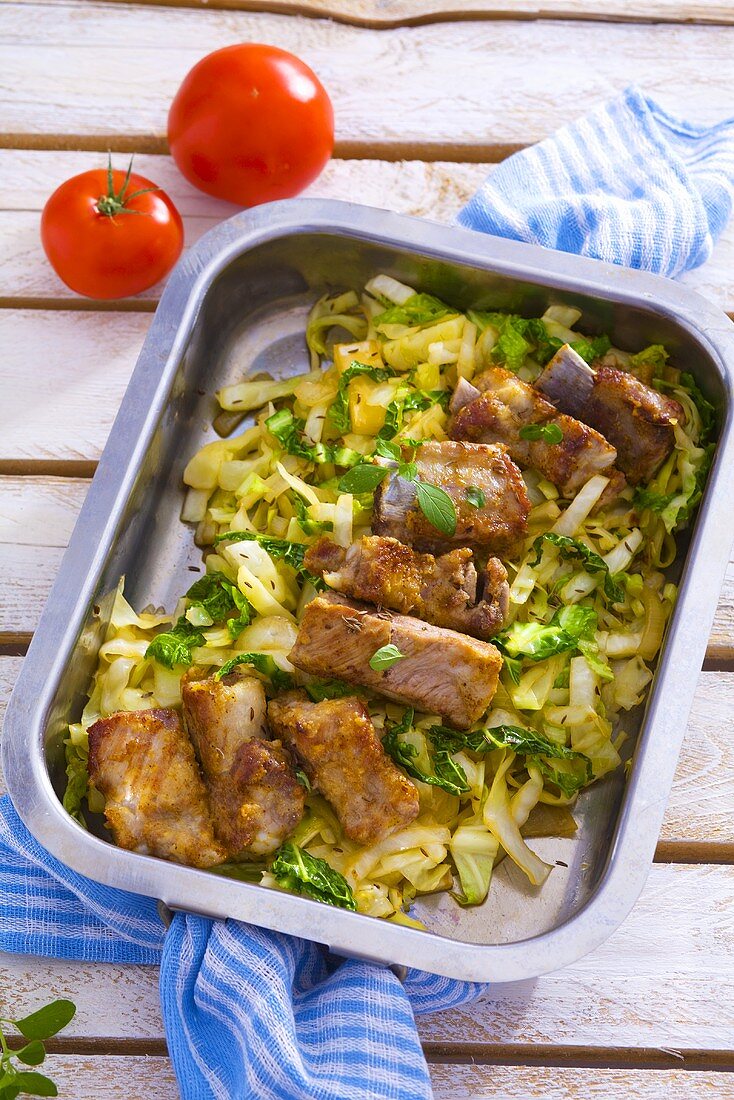 Roasted pork ribs with cabbage in roasting tin