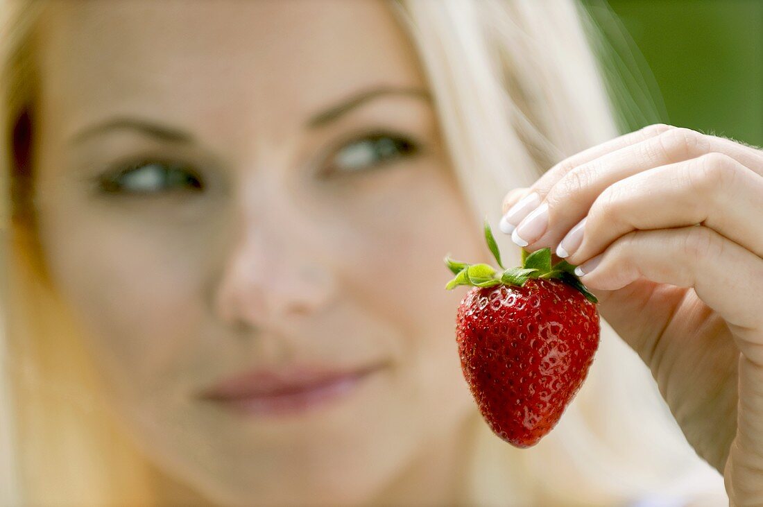 Frau hält Erdbeere