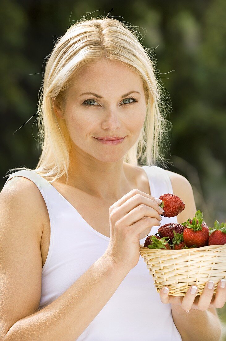 Blonde Frau hält Korb mit Erdbeeren