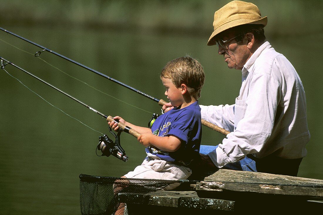A grandfather and grandson fishing at a lake