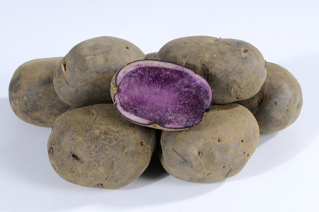 Several potatoes (variety 'Blue Congo'), whole and halved