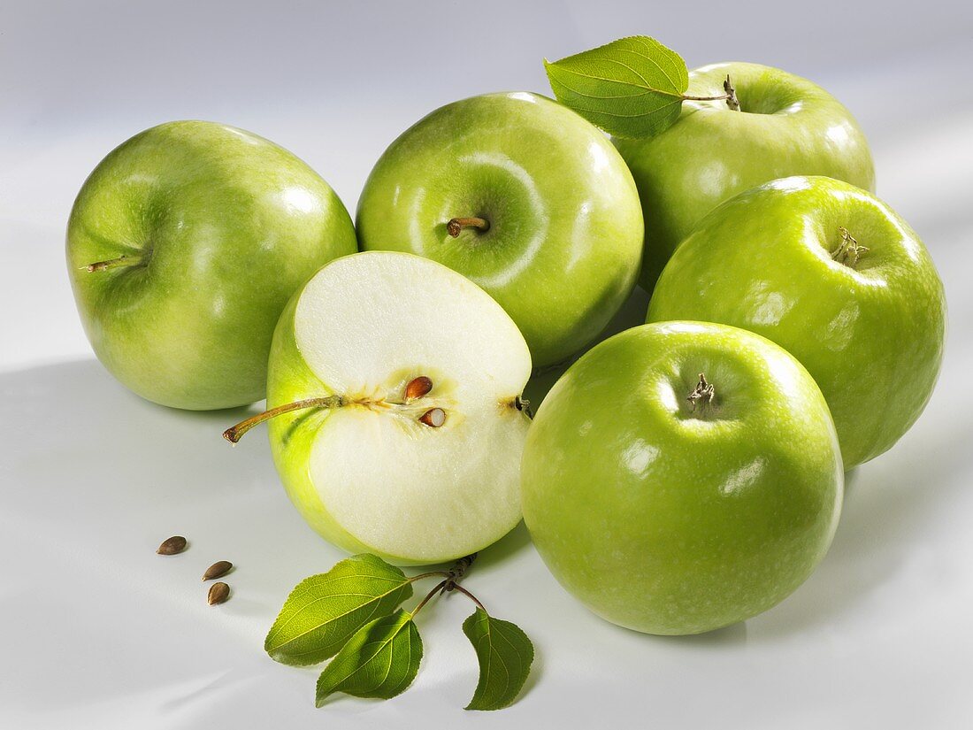 Mehrere grüne Äpfel (ganz und halbiert)
