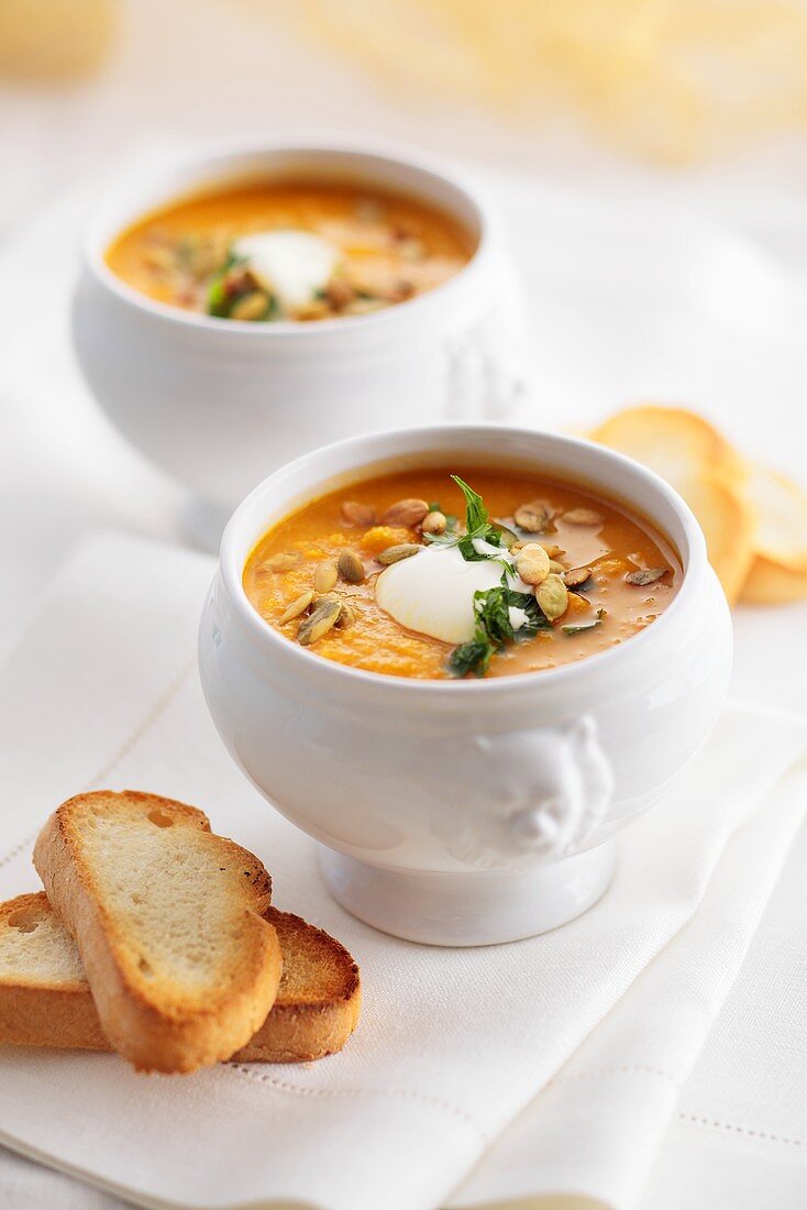 Pumpkin and orange soup with pumpkin seeds and sour cream