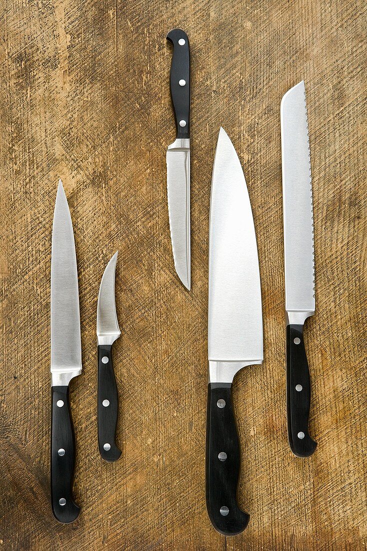 Assorted kitchen knives on wooden background