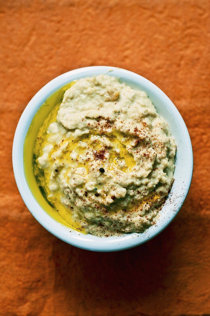 Hummus mit Olivenöl in hellblauer Schale (Draufsicht)