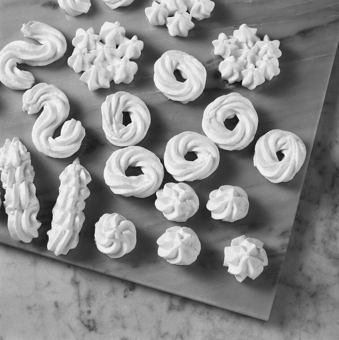 Meringue in various shapes drying on marble slab