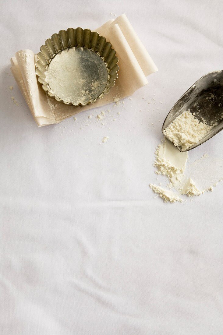 Tart tin, baking parchment and scoop with flour