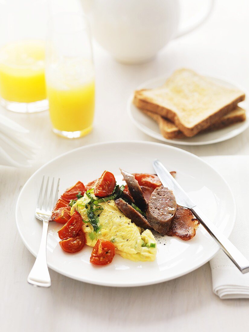 Omelett mit Tomaten, Wurst und Bacon zum Frühstück