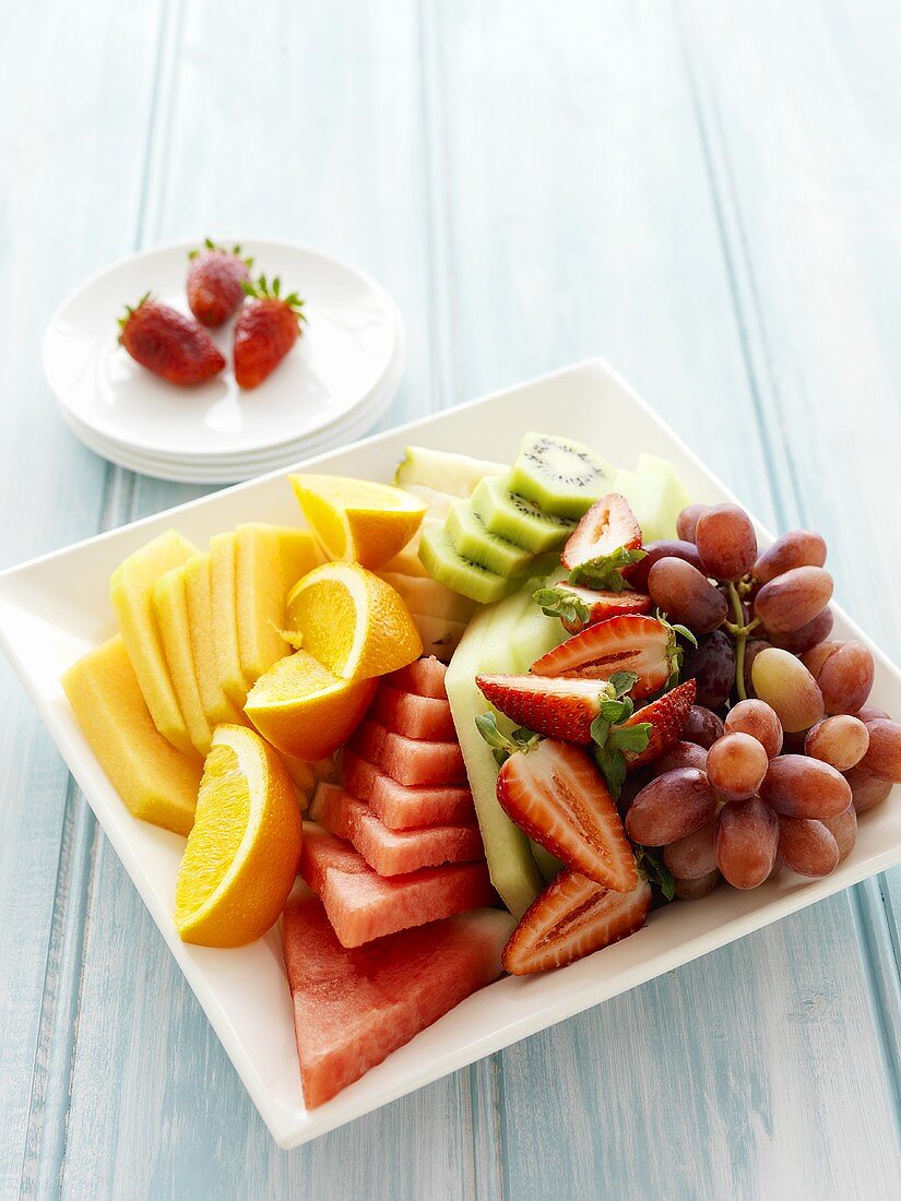 Obstteller mit Orangen, Melone, Erdbeeren und Trauben