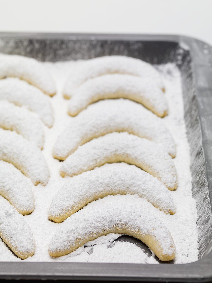 Vanilla crescents with icing sugar on baking tray