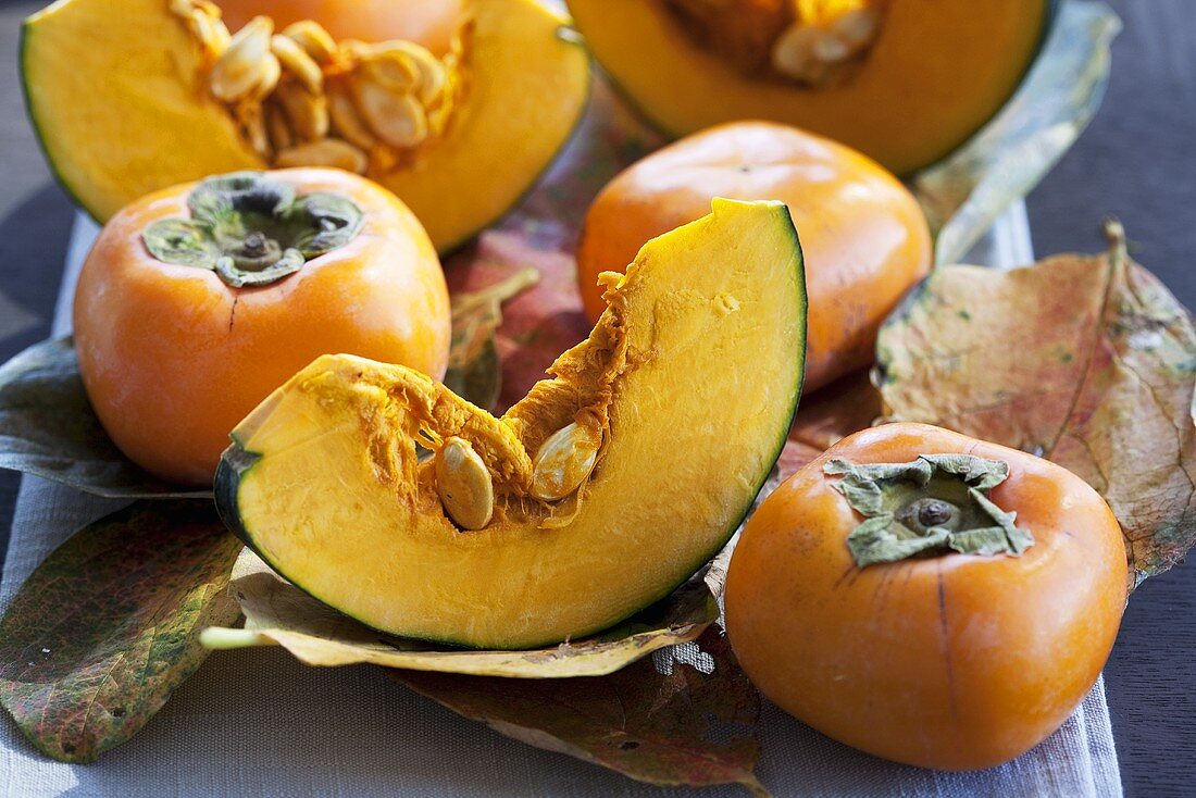 Japanese persimmons and pumpkin slices on autumnal leaves