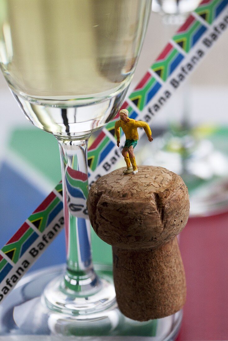 Champagne glass, cork and a toy football player