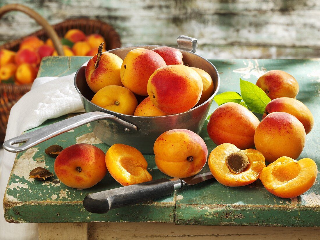 Apricots in pan, on wooden table and in basket