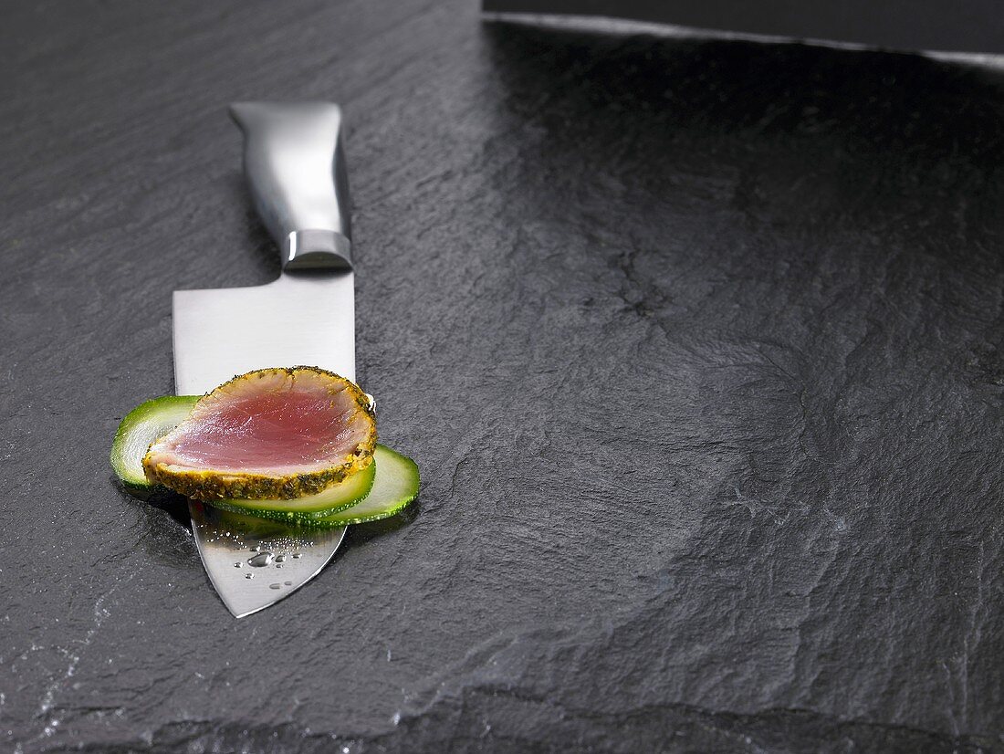 Santoku knife with slice of tuna and slices of vegetables