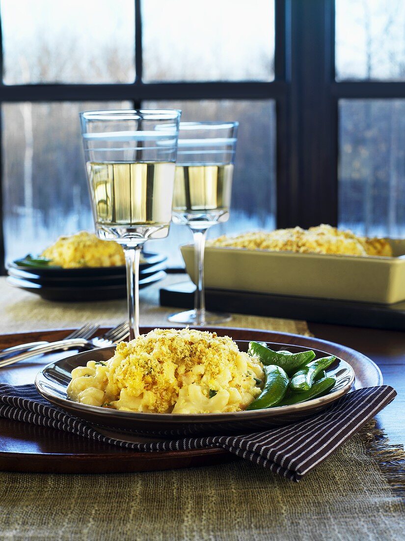 Macaroni and cheese with mangetout and glasses of white wine