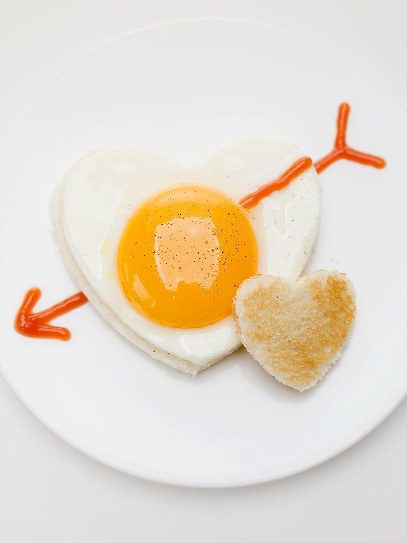 Heart-shaped fried egg with ketchup arrow and heart-shaped toast