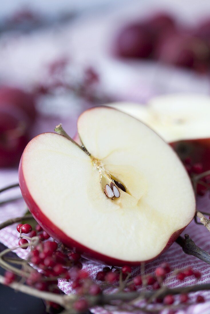 Halber Apfel und Schneeballbeeren auf Geschirrtuch