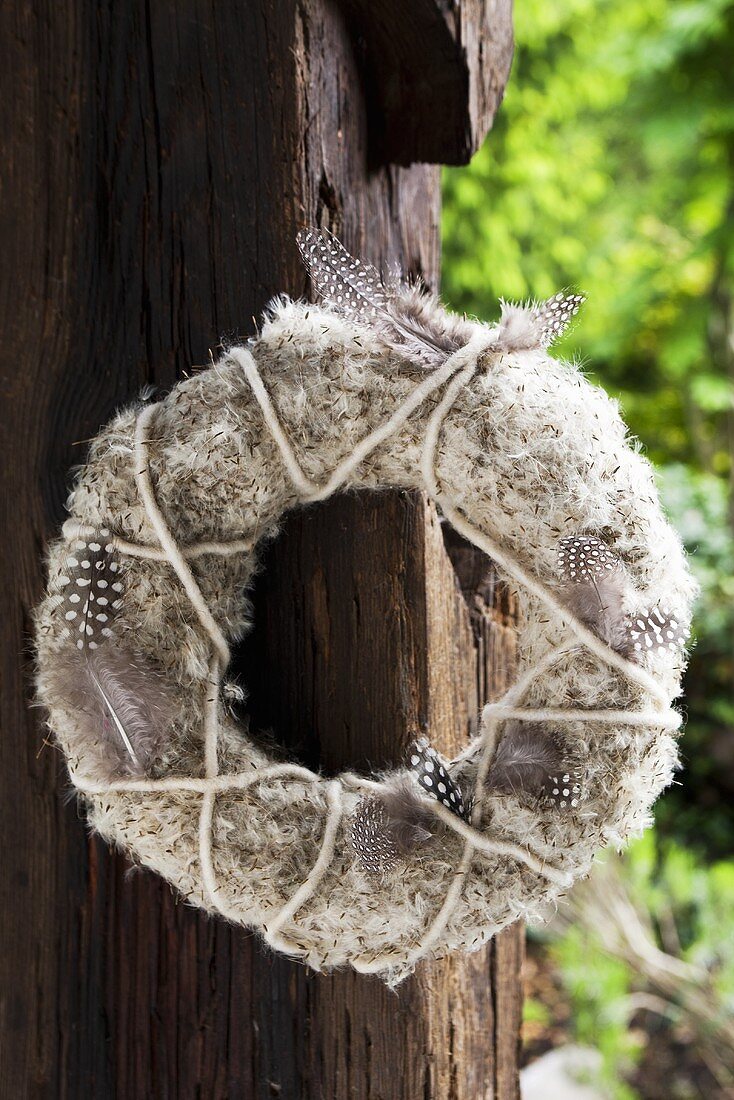 A door wreath of dandelion clocks, guinea fowl feathers and felt yarn