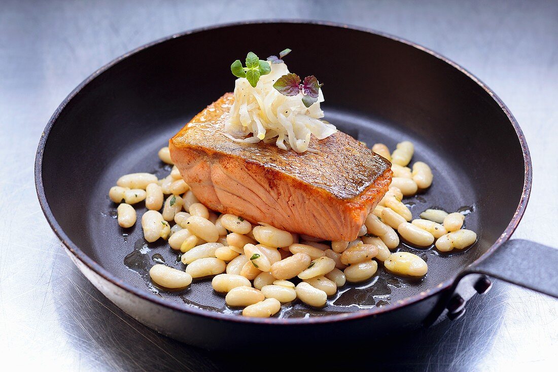 Fried salmon fillet with white beans in frying pan