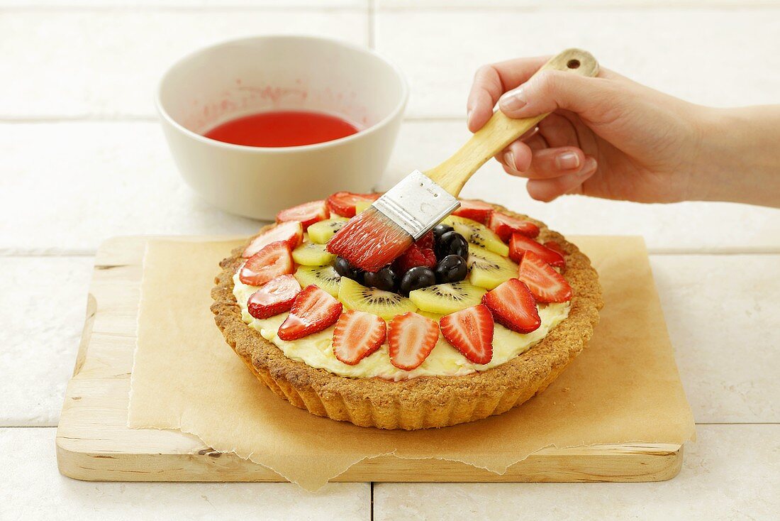 Brushing a fruit flan with cake glaze