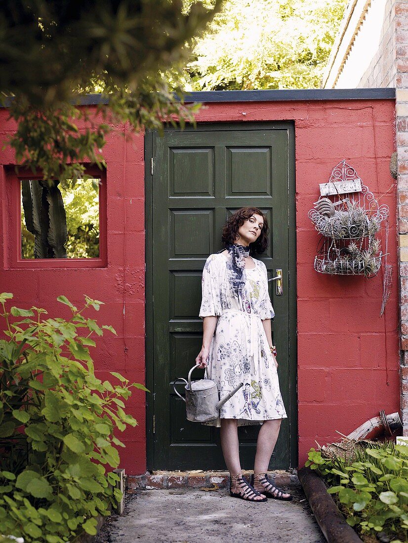 Woman with watering can standing by door