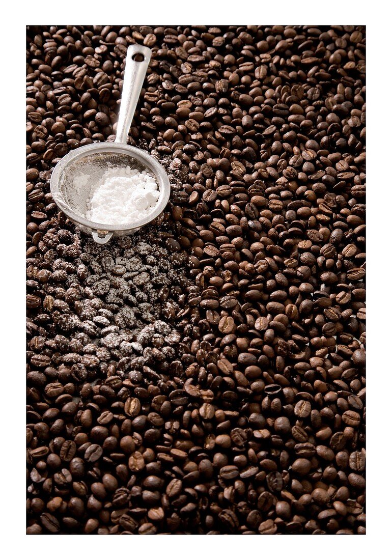 Sieve full of icing sugar on coffee beans