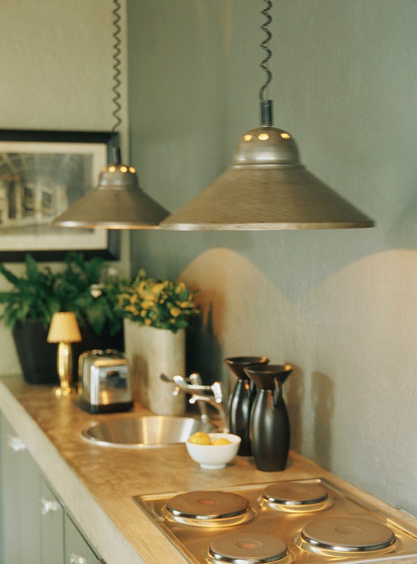 Kitchen counter with pendant lamps above hob and round sink in concrete worksurface