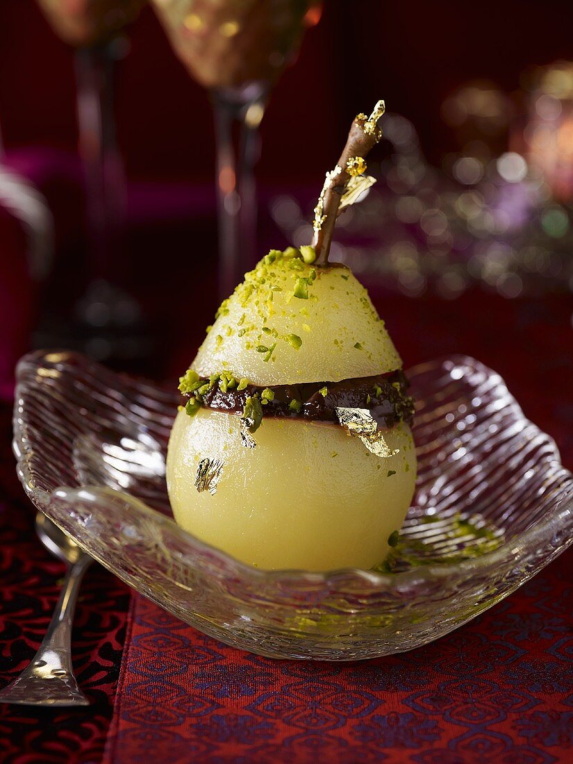 A poached pear with chocolate, gold leaf and pistachios