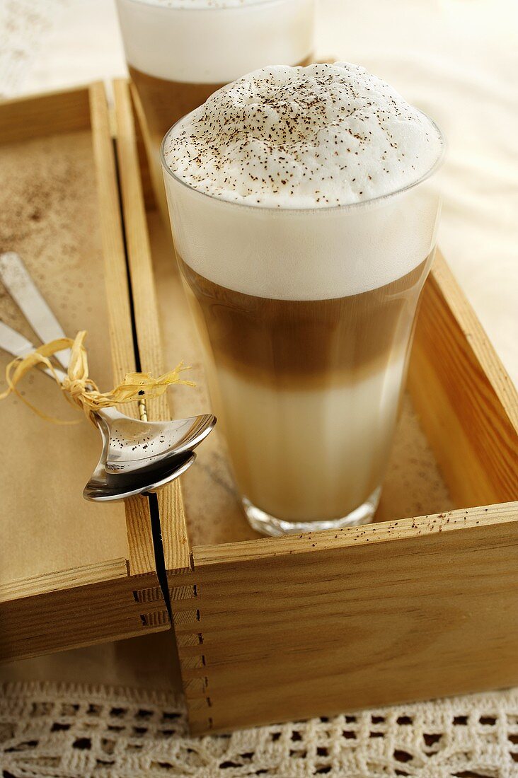 Two glass of latte macchicato in a wooden box