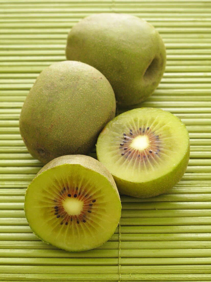 Chinese kiwis, whole and halved, on a bamboo mat
