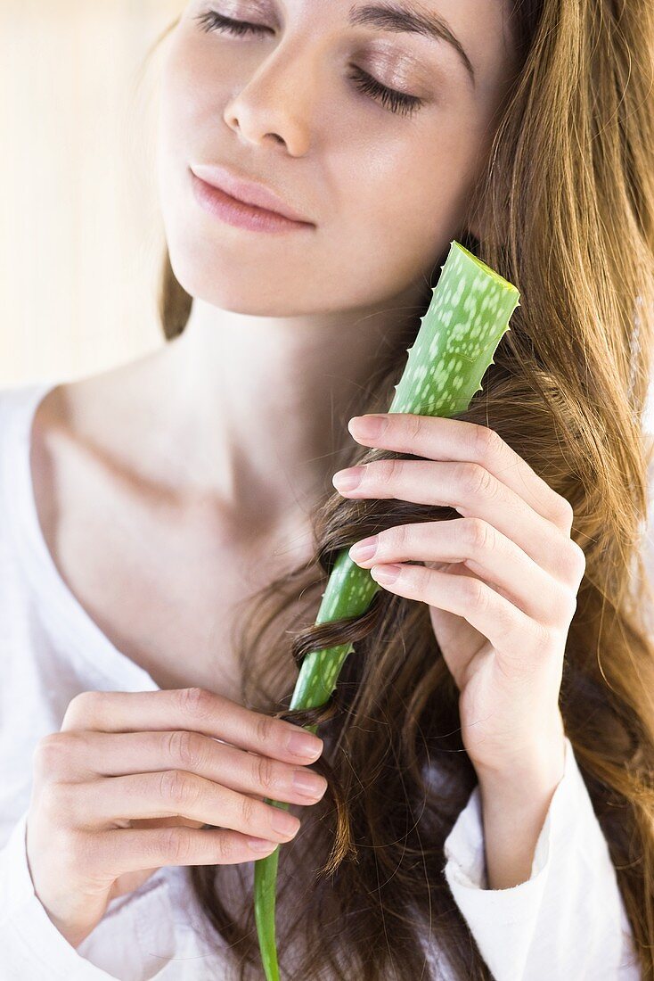 A woman wrapping her hair around an aloe vera leaf