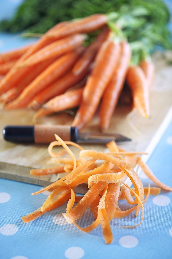Carrot skins, a peeler and fresh carrots