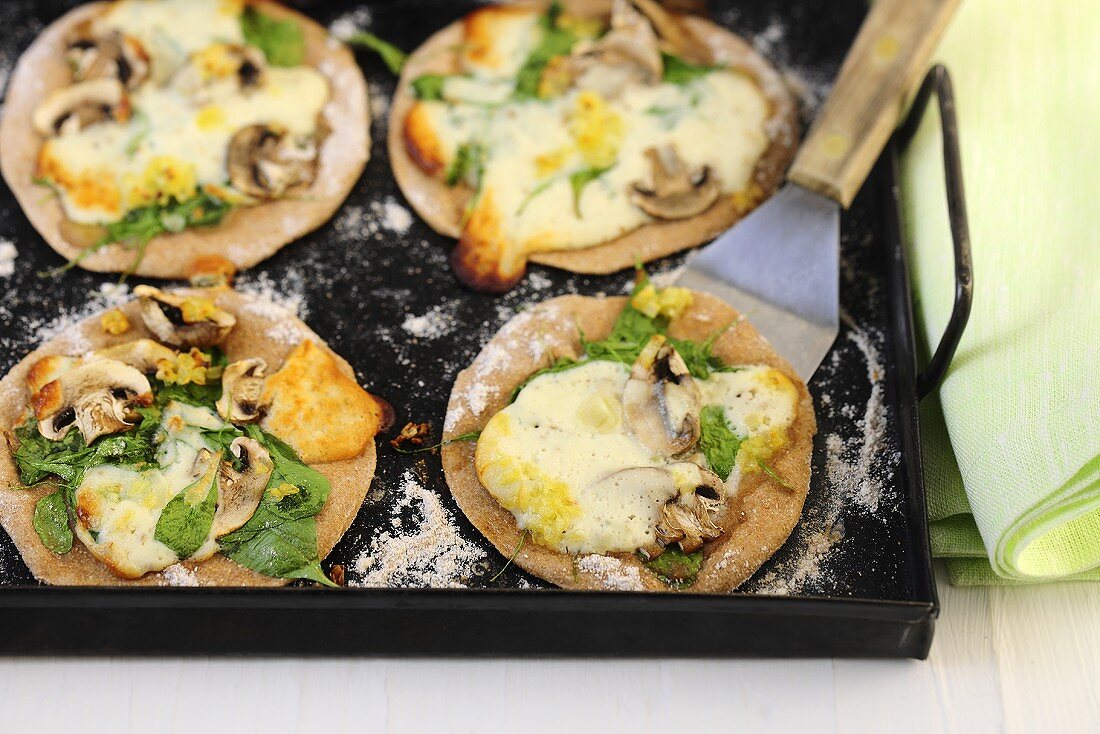 Mini pizzas with spinach, mushrooms and cheese
