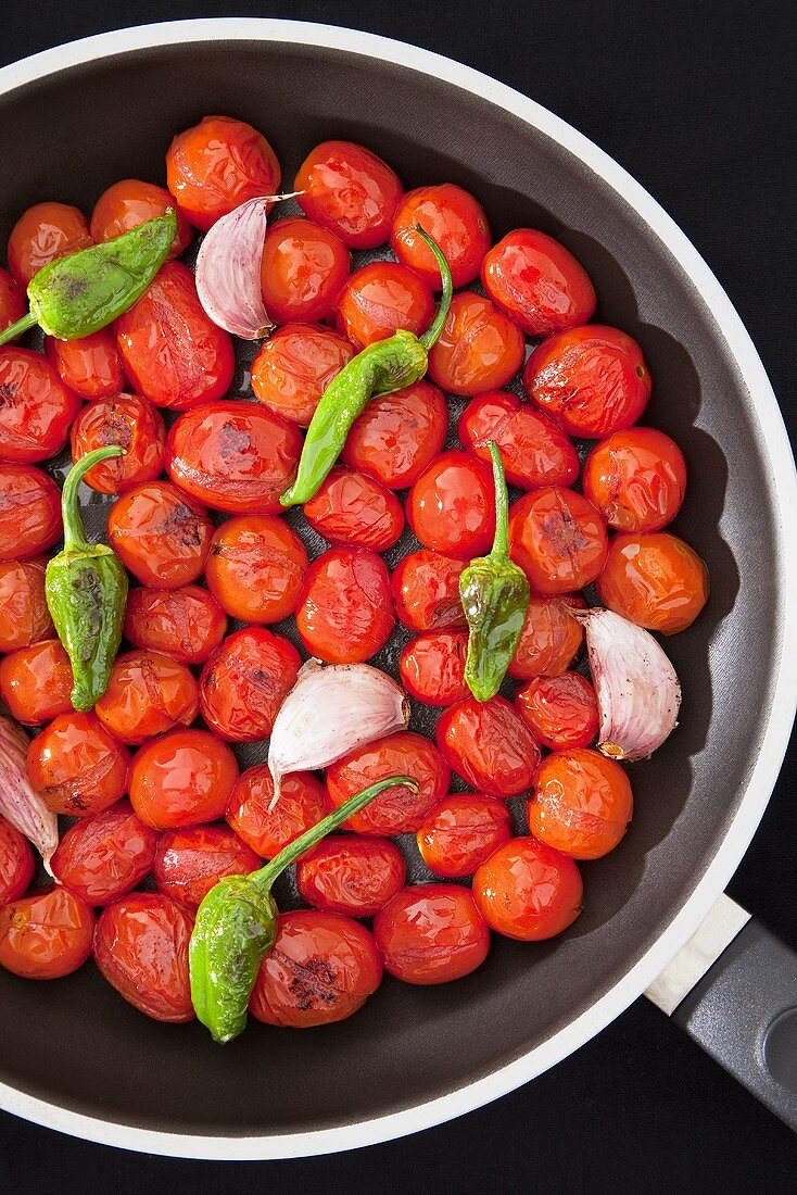 Roasted cherry tomatoes with chilli peppers and garlic in a pan