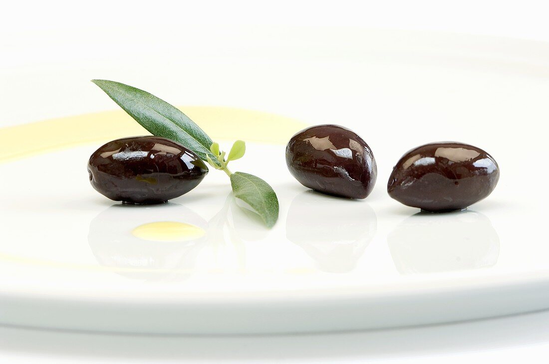 Kalamata-Oliven mit Blatt und Olivenöl auf Teller