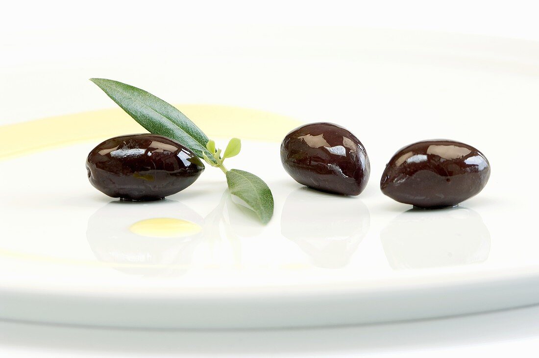 Kalamata olives with leaves and olive oil on a plate