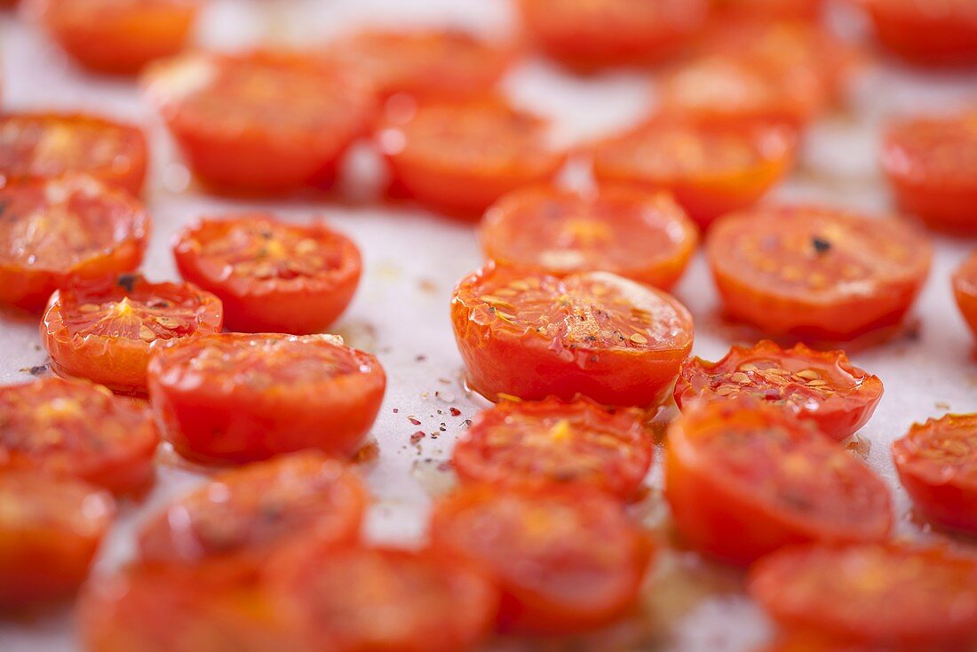 Halved, roasted cherry tomatoes on a baking tray