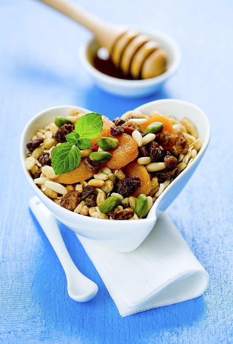 Muesli with dried fruit and honey in a heart-shaped bowl