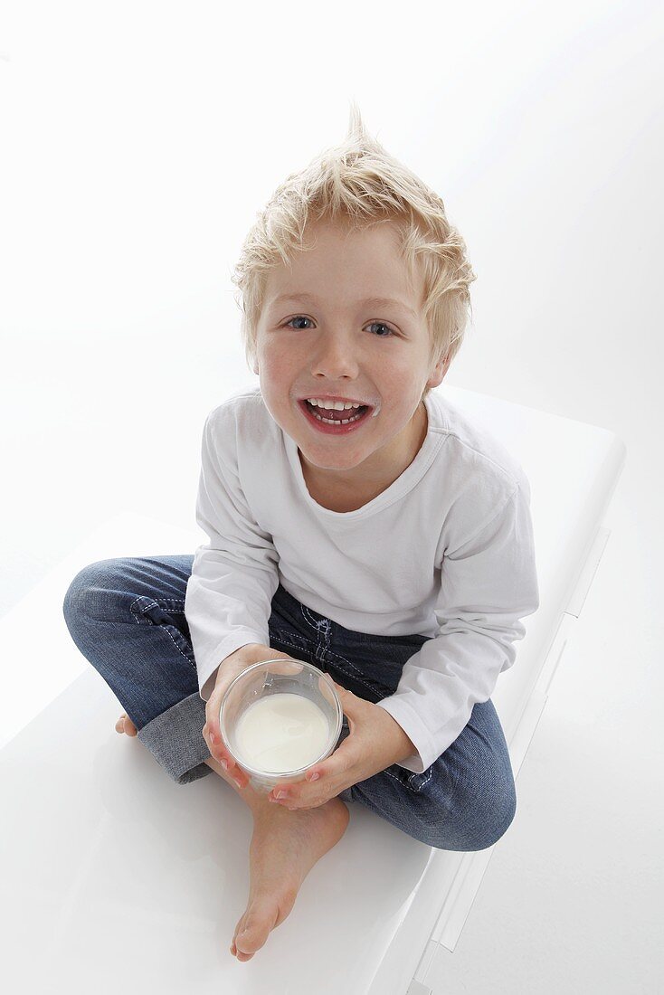 A little boy holding a glass of milk