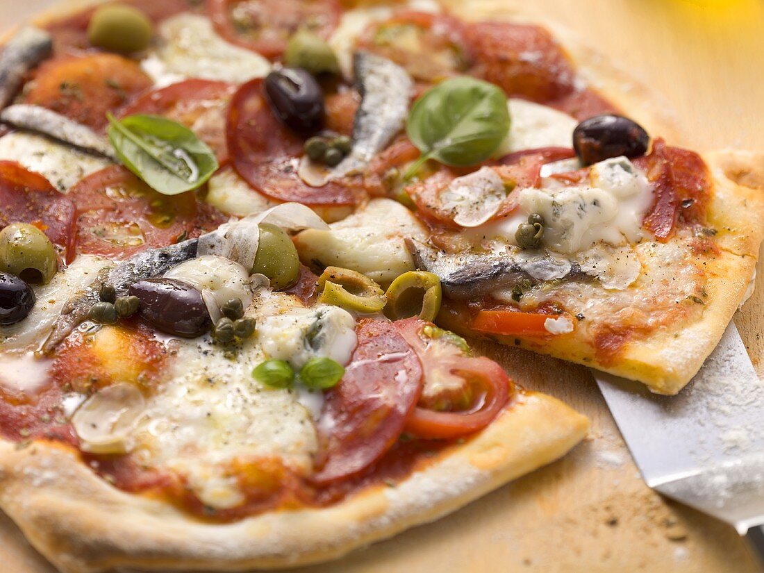 Tomato pizza with salami, gorgonzola, sardines and olives