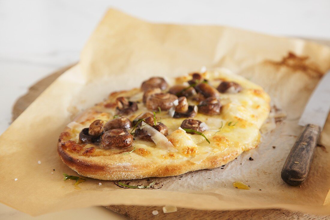 Small mushroom and Pecorino pizza on baking parchment